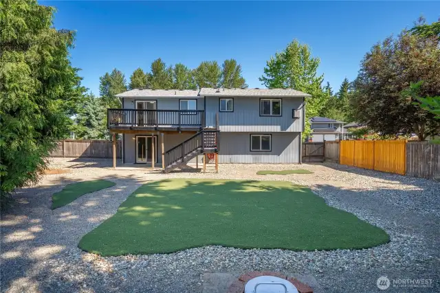 Enjoy a large, no-maintenance backyard with artificial grass & wood burning fire pit—more space, less work!