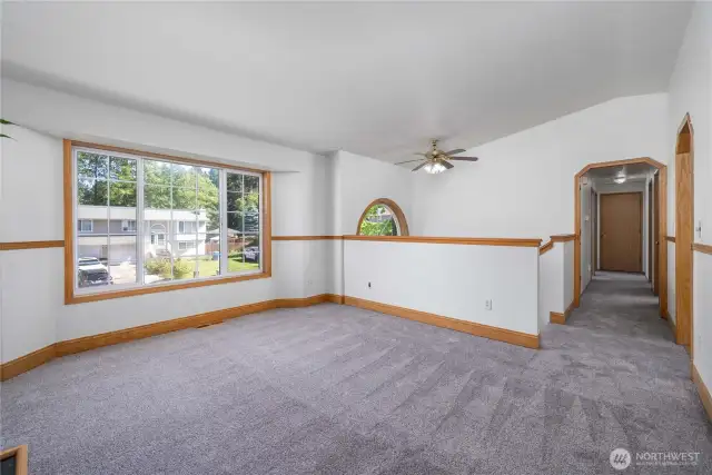 Living area with a large window and ceiling fan. Fresh interior pain and brand new carpet!