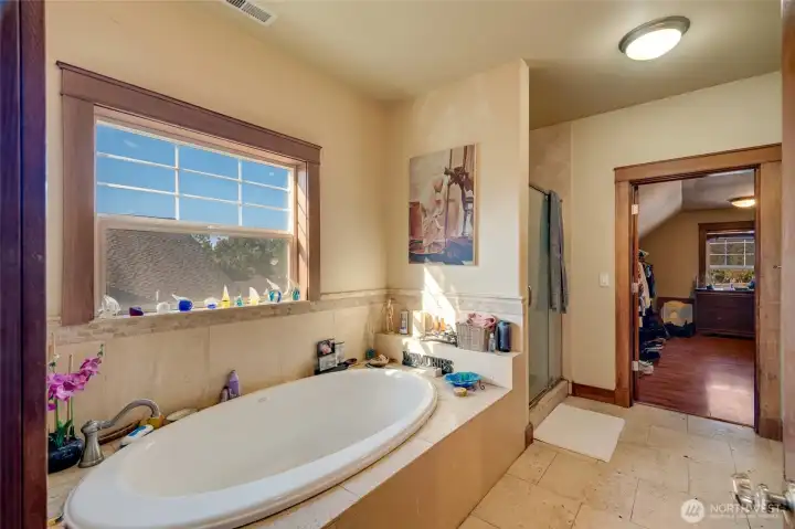 Primary en suite bath with a soaker tub, travertine shower and access to an enormous closet room.