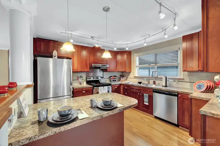 Updated, modern kitchen. Island with storage space and sitting area. Custom cabinets w/ custom handles and easy close drawers for your convenience. Easy care planked flooring in kitchen, living, dining rooms and hallway.