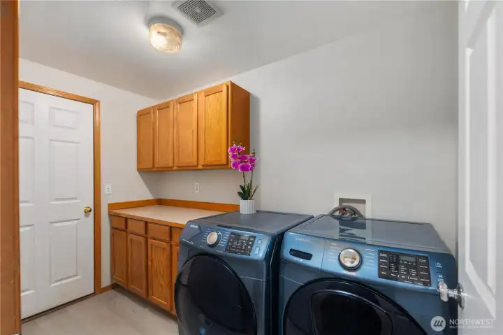 Laundry room with newer washer and dryer and extra storage cabinets.