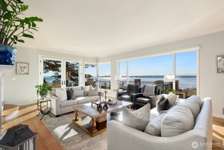 Entertain effortlessly in the formal dining room and spacious living room with gas fireplace and wood-planked top-nail hardwoods. French doors open to a view deck—perfect for sunset dinners—while expansive windows frame breathtaking water and mountain vistas from nearly every room.