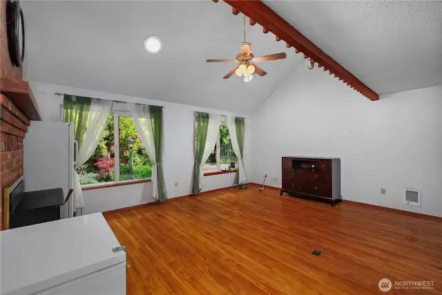 Open Great room with vaulted ceiling, fireplace and ceiling fan.