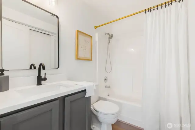 This crisp and clean bathroom features a new vanity counter, matte black fixtures, stylish lighting, and fresh trim—all complemented by neutral tones and timeless finishes.