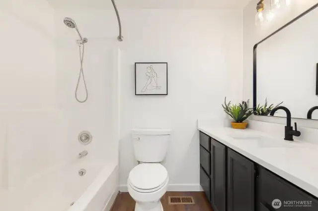 This primary full bath continues the trend of thoughtful upgrades with a new quartz-style counter, modern matte black fixtures, fresh trim, and clean design—perfect for guests or daily routines.