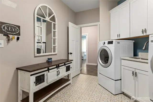 Large laundry/mud room with deep sink & access through to primary bedroom
