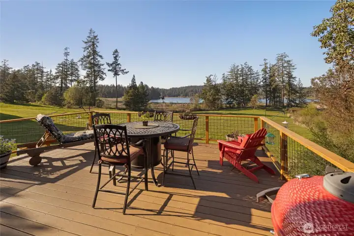 Spacious entertaining deck with sweeping views of the water and surrounding forest, perfect for dining, relaxing, or taking in sunsets.