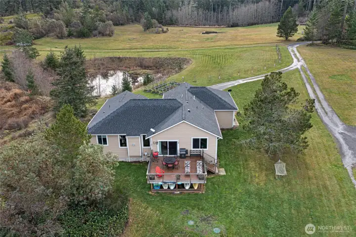 A stunning aerial view highlights the private 2-acre property, complete with a pond, manicured lawn, and wooded backdrop leading to the shoreline.