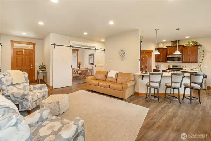 Open-concept living space flows seamlessly into the kitchen and dining area, with bar seating for casual meals and gatherings. Modern lighting and wood accents create a warm, inviting atmosphere.