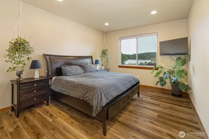 Spacious primary suite with large picture window overlooking tranquil water views, creating a peaceful retreat to wake up and unwind in.