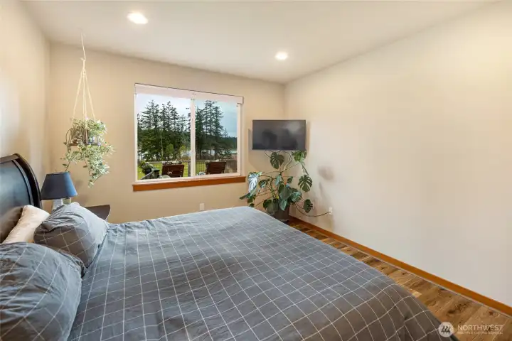 Spacious primary suite with large picture window overlooking tranquil water views, creating a peaceful retreat to wake up and unwind in.