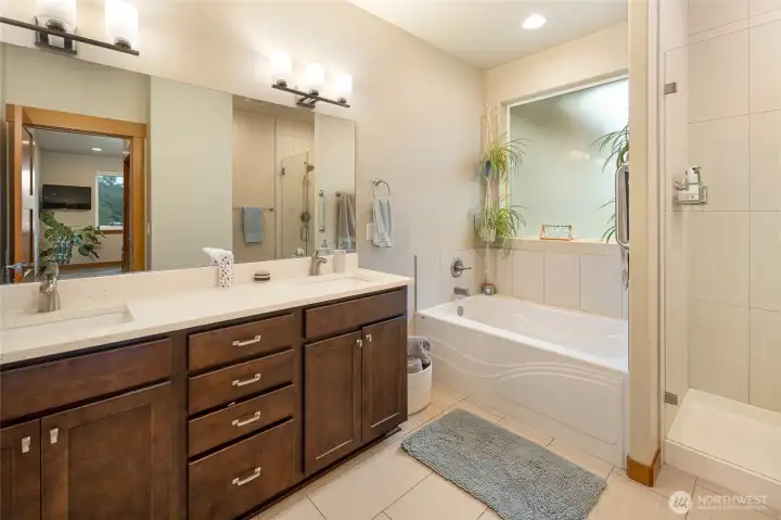 Bright, spa-like bathroom featuring a soaking tub, dual vanities with ample storage, and elegant finishes throughout.