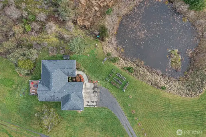 Charming single-story home with attached garage, framed by a reflective pond and open green space