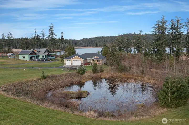 Charming single-story home with attached garage, framed by a reflective pond and open green space
