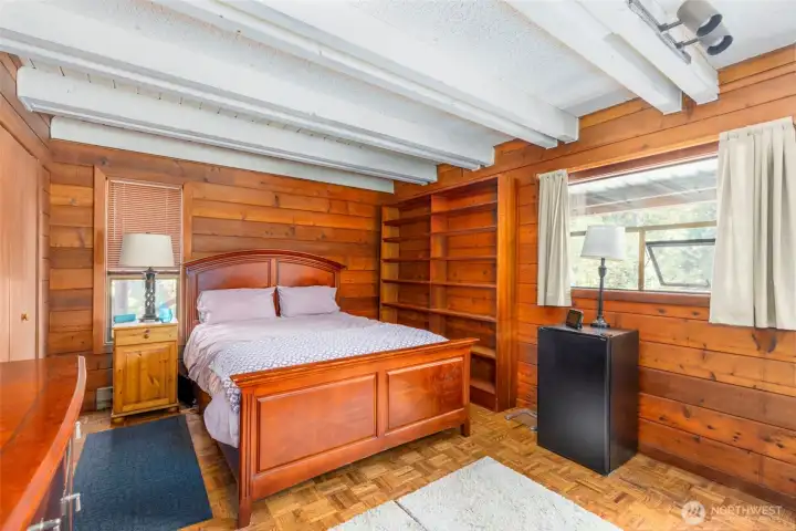 A smaller bedroom with lovely wood floor and natural wood interior walls.