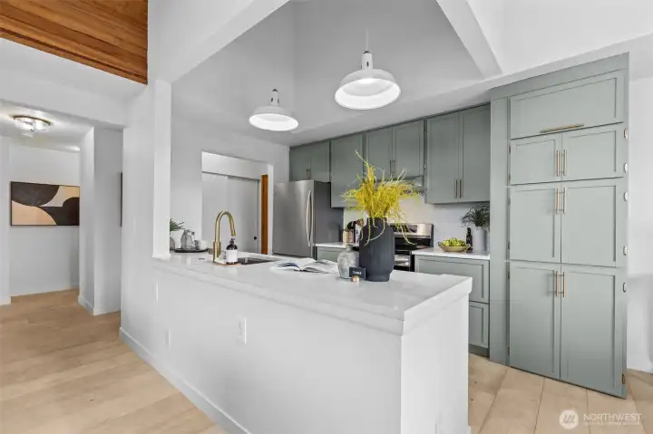 Custom, remodeled kitchen with quartz countertops, sage-green cabinetry, scalloped ceramic tiles, stainless steel appliances.