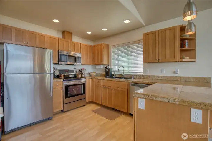 The kitchen is well appointed with stainless steel appliances, quartz tile countertops, and shaker cabinets.
