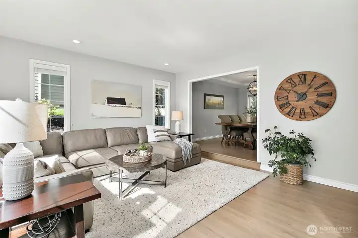 Living room with large front windows, abundant natural light, neutral wall color, recessed lighting, barn door, and spacious seating area.