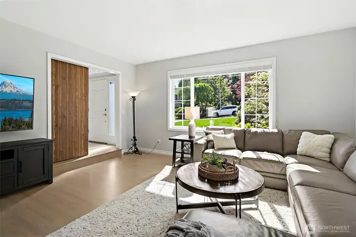 Living room with large front windows, abundant natural light, neutral wall color, recessed lighting, barn door, and spacious seating area.