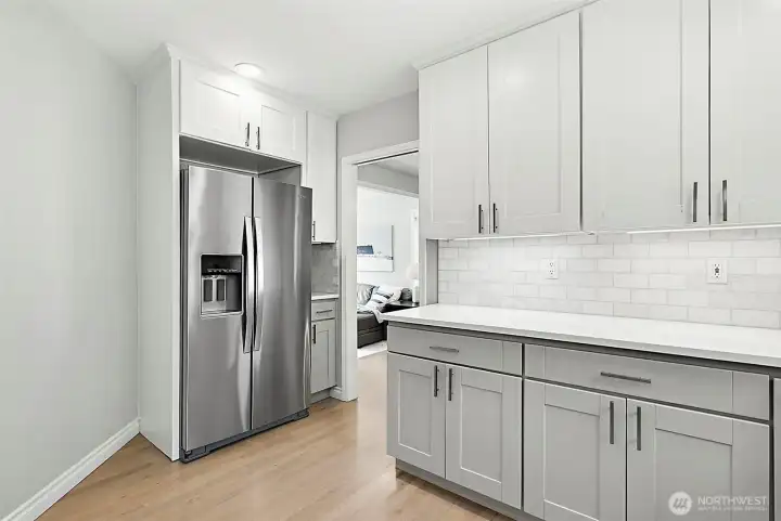 Chef’s kitchen with quartz countertops, subway tile backsplash, two-tone shaker cabinets, stainless appliances, recessed lighting, and backyard views.