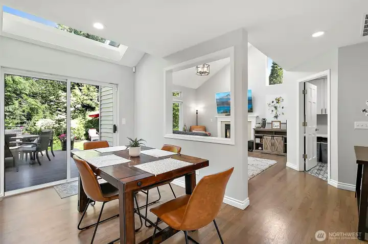 Breakfast dining area with skylight, hardwood flooring, sliding door access to the new deck, backyard views, and open flow to nearby living spaces.