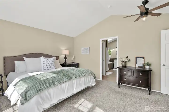 Primary bedroom with vaulted ceiling, arched windows, natural light, neutral finishes, carpet flooring, and spacious layout.
