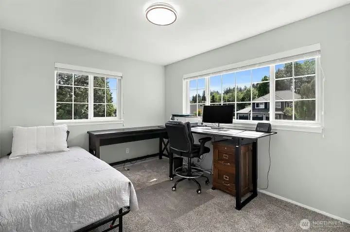 Additional bedroom with large window, neutral wall color, carpet flooring, overhead lighting, and flexible space for guests, work, or hobbies.