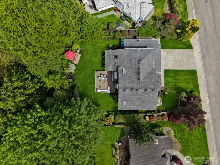 Aerial view of North Bend home with attached 2-car garage, landscaped front yard, long driveway, fenced backyard, and greenbelt backdrop.