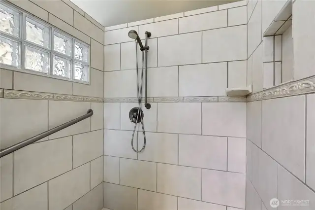 Primary bath shower, love the tile and glass block, I could stand here all day! Convenient built-ins.