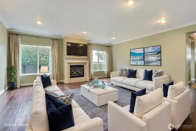 Great room view, LOVE the hardwood floors and crown molding in this home. One of two fireplaces here, large windows, entry to your right. ***Virtually Staged***