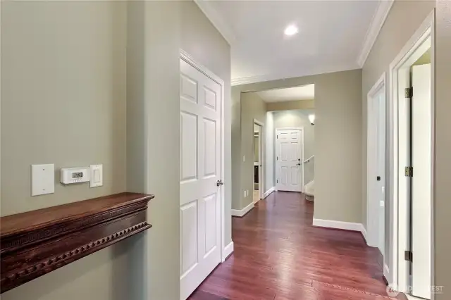 Hallway view from Primary Suite, kids/guest bath and bedroom to your right, linen closet to your left, straight ahead is your utility room, garage door and stairs up to massive bonus room.