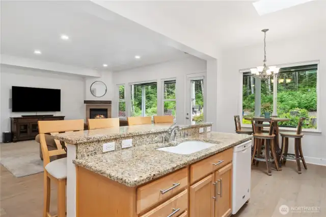 The island kitchen is a focal point for gatherings and conversation. Granite counters, newer hardware throughout and new skylights enhance the room.