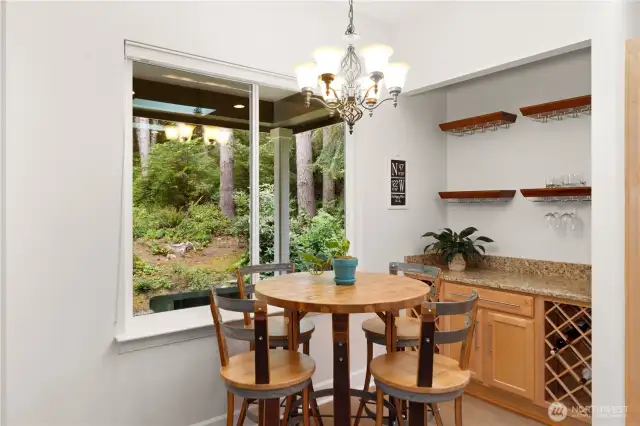 The bar area and eating nook enjoy peaceful views of the lovely back yard and woods.