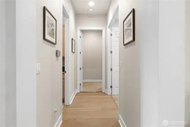 The wide main hallway leads to a den on the right, the utility room and garage on the left, and straight ahead is the spacious, primary ensuite.