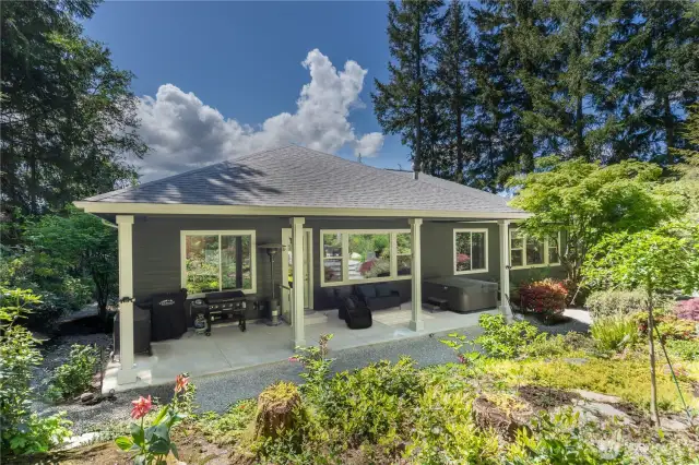 The calming private back yard is a sunny oasis. Under the covered porch you'll find a hot tub, seating area, and a propane hook-up for all of your barbecuing needs.