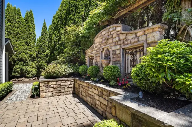 Custom metal wall art with water feature adds ambiance to the backyard. Storage shed to the left of the picture.