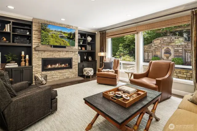 Warm and inviting family room has custom, built-in shelving and massive wall of windows to enjoy the exterior garden and water features. Mendota 47" gas fireplace adds ambiance to the room.