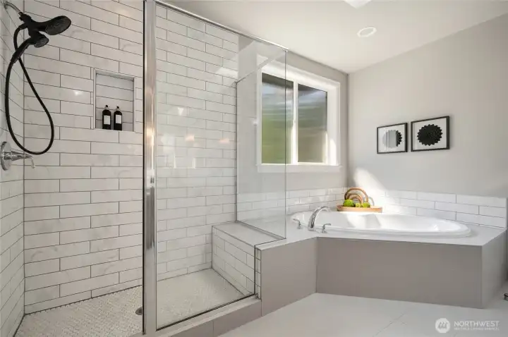 Primary suite boasts a spa-like bath with custom tile and glass surround shower with sitting bench and a luxurious soaking tub.