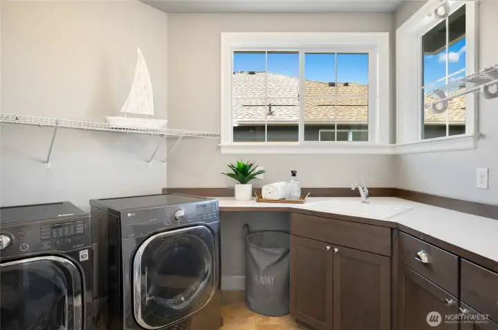 Jaw dropping Laundry Master's dream laundry room with utility sink, built-in cabinets, and countertop space for laundry prep.