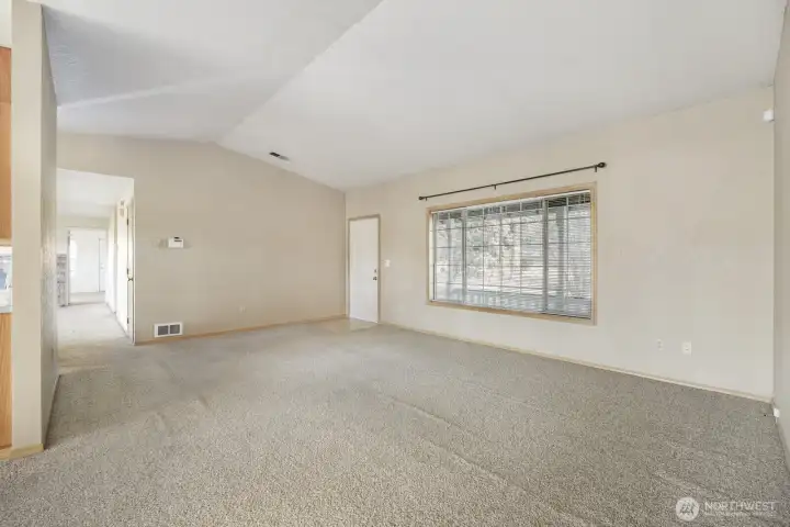 The spacious living room showing the front door and the vaulted ceiling.
