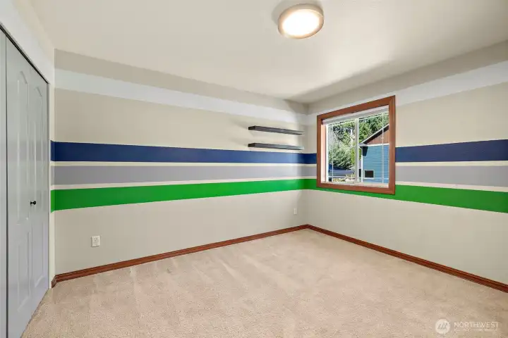 Secondary bedroom with custom painted stripes. Window to the front yard. Not pictured custom built in closet