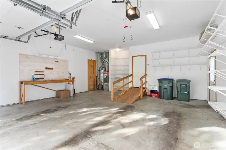Oversized garage with workbench and ramp for no stairs entry.