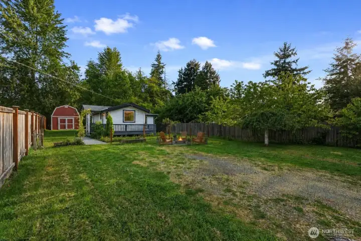 From the driveway, you get a wonderful sense of the property’s size and privacy—mature evergreens and a wooden fence line the back and side boundaries, creating a peaceful, park-like setting. Plenty of room for future improvements like additional gravel, pavers, or even a carport if desired.