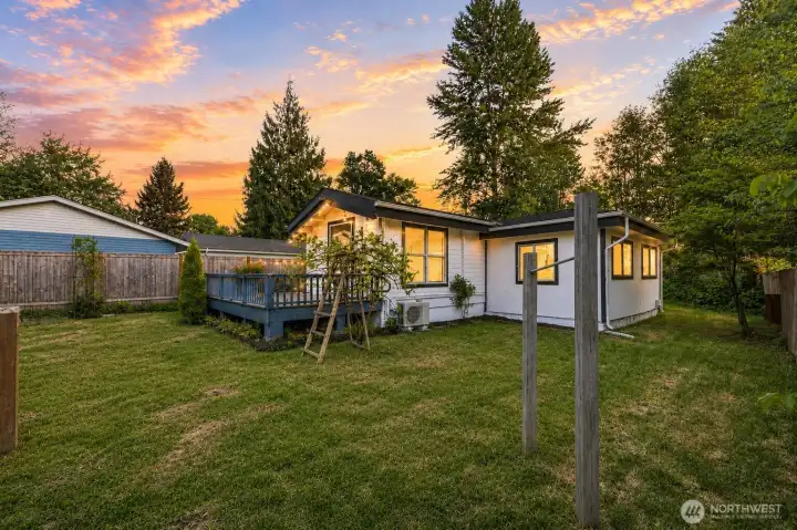 The front yard of this charming home offers a spacious, level expanse of lush lawn framed by mature trees and thoughtful landscaping, creating an inviting and private first impression. A generous wooden deck with railing extends from the house, perfect for morning coffee or evening relaxation while overlooking the yard. Abundant natural light, mature evergreens provide beauty, while the wide gravel driveway runs alongside for convenient access and ample off-street parking, including room for an RV. This welcoming front yard blends functionality with natural charm, setting a peaceful tone for the entire property.