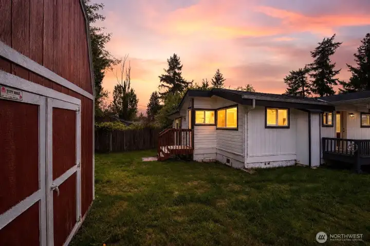 Expansive backyard setting offers a wonderful blend of open green space, natural light, and practical functionality. The oversized red storage shed with lofted storage dramatically enhances the property with exceptional space for hobbies, tools, equipment, or workshop potential, while the home's inviting rear entry and deck create an ideal setup for relaxing, entertaining, and enjoying the peaceful outdoor surroundings.