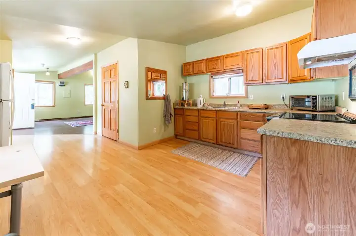 Large open kitchen with ample cabinetry, granite-look counters, stainless appliances, and direct sightlines to the living area. Oversized pantry door at left.