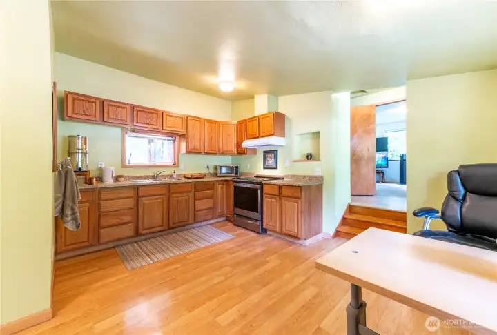 Kitchen from the dining area, looking towards bonus room. Functional L-layout with stainless range, hood, and plenty of prep and storage space.