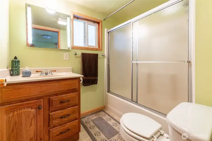 Full bathroom with tub/shower combo and oak vanity.