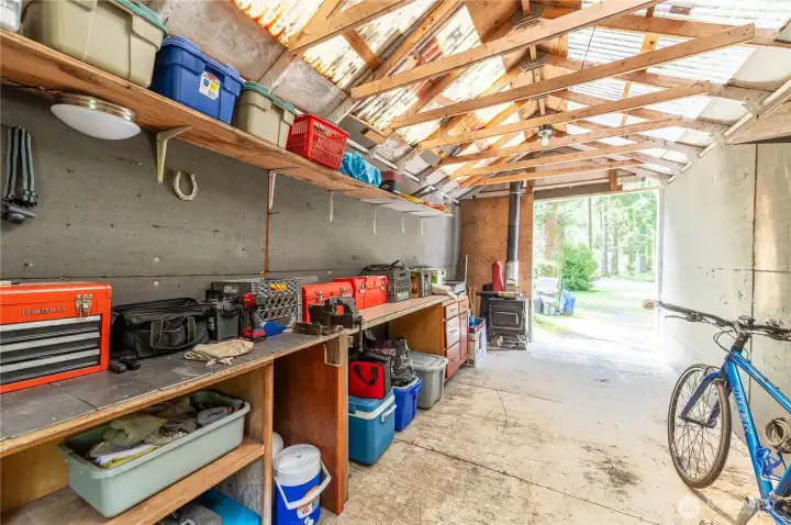 Shop interior with workbench, shelving, and wood stove. This is the kind of space that makes a recreational property genuinely functional.