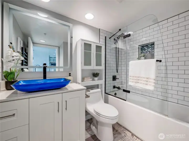 Timeless white tile, designer fixtures, and an anti-fog mirror create a clean, spa-inspired bath.